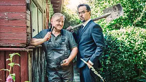 Axel Prahl steht im Blaumann und Jan Josef Liefers im Anzug in einem Schrebergarten. Beide halten Werkzeuge in der Hand. - Foto: WDR/Bavaria Fiction GmbH/Taimas Ahangari Axel Prahl steht im Blaumann und Jan Josef Liefers im Anzug in einem Schrebergarten. Beide halten Werkzeuge in der Hand. - Foto: WDR/Bavaria Fiction GmbH/Taimas Ahangari