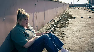 Stefanie Reinsperger sitzt auf einem Dach und sieht traurig aus. - Foto: WDR/Thomas Kost