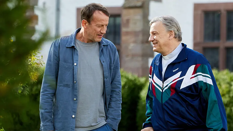 Tatort - Schweigen Wotan Wilke Möhring steht für den Hamburg „Tatort: Schweigen“ neben einem sportlich gekleideten Pfarrer.