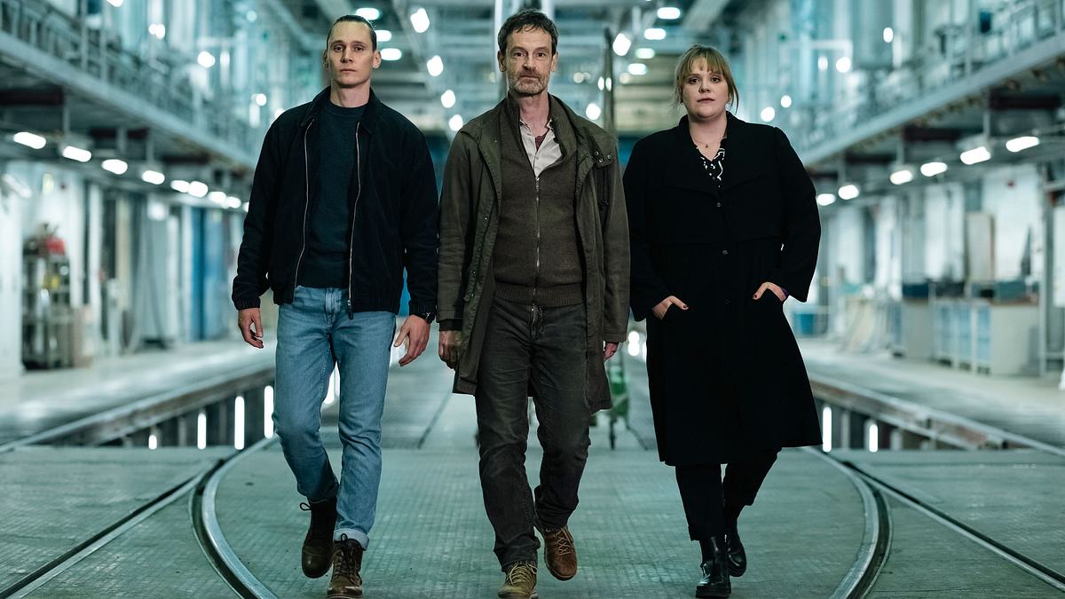 Tatort – Love is pain Von links nach rechts gegen Rick Okon, Jörg Hartmann und Stefanie Reinsperger durch eine Art Lagerhalle.