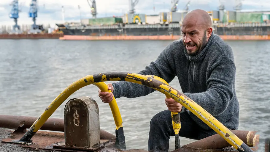 Dar Salim steigt als Mads Andersen am Hafen an einer Leiter zurück an Land.