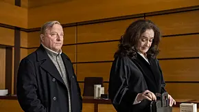 Axel Prahl und Mechthild Großmann stehen für den Münsteraner „Tatort“ in einem Gerichtssaal. - Foto: MDR/WDR/Martin Valentin Menke