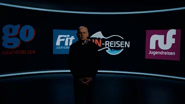 Günther Wallraff steht in einem dunklen Studio vor einer gebogenen Wand mit Logos von Jugendreiseanbietern. - Foto: RTL Günther Wallraff steht in einem dunklen Studio vor einer gebogenen Wand mit Logos von Jugendreiseanbietern. - Foto: RTL