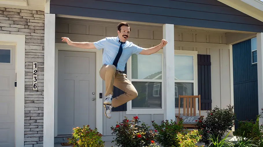 Ted freut sich auf sein Fußball-Comeback. Ted Lasso bringt vor seinem Haus über Büsche.
