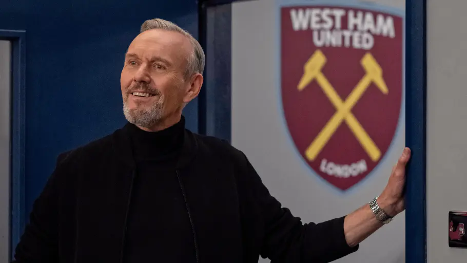 Rupert steht im West Ham-Umkleideszimmer und lächelt zufrieden.