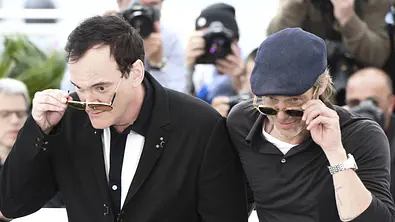 Brad Pitt und Quentin Tarantino werden in Cannes fotografiert. Sie machen beide dieselbe Pose mit ihren Sonnenbrillen. - Foto: IMAGO / Panoramic by PsnewZ