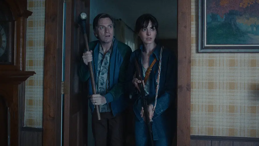 The End of Oak Street Anne Hathaway und Ewan McGregor schauen schockiert in einen Raum. Beide sind bewaffnet.