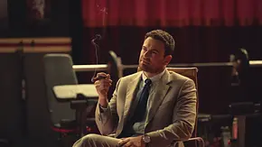 Theo James raucht in The Gentleman eine Zigarre und sitzt auf einem Stuhl - Foto: Netflix Theo James raucht in The Gentleman eine Zigarre und sitzt auf einem Stuhl - Foto: Netflix