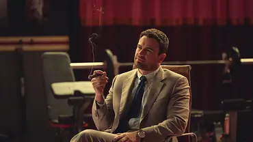 Theo James raucht in The Gentleman eine Zigarre und sitzt auf einem Stuhl - Foto: Netflix