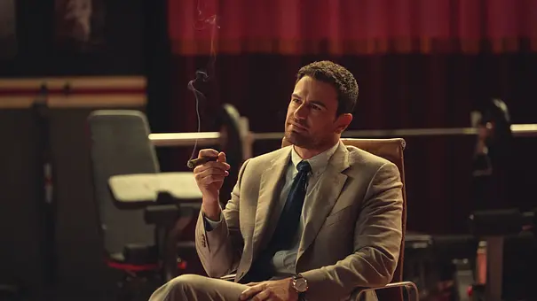 Theo James raucht in The Gentleman eine Zigarre und sitzt auf einem Stuhl - Foto: Netflix