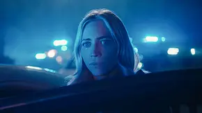 Brittany Snow blickt als Sophie hinter einer Autotür hervor. Blaues Licht beleuchtet ihr Gesicht, im Hintergrund leuchten Blaulichter. - Foto: Netflix Brittany Snow blickt als Sophie hinter einer Autotür hervor. Blaues Licht beleuchtet ihr Gesicht, im Hintergrund leuchten Blaulichter. - Foto: Netflix
