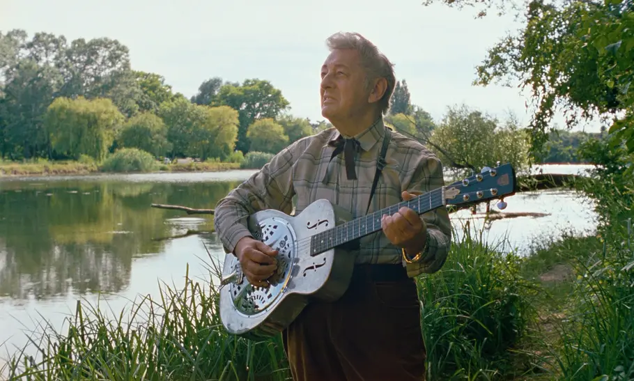 Alois Koch steht mit einer Blues-Gitarre an der Donau.