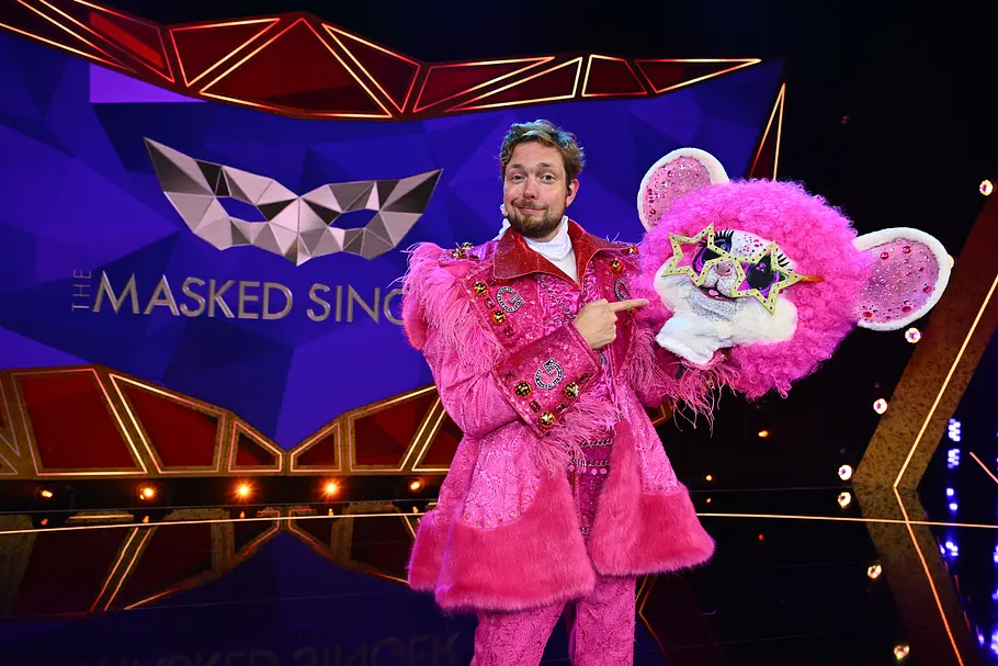 Bastian Bielendorfer brachte Groovy zum Tanzen Bastian Bielendorfer trägt ein pinkes Kostüm und zeigt auf einen pinken Tiermaskenkopf mit Sternenbrille bei „The Masked Singer“.