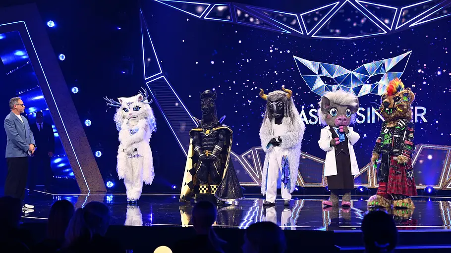 „The Masked Singer“ 2026 Finale Matthias Opdenhövel und fünf aufwendig kostümierte Figuren stehen auf einer blau beleuchteten Showbühne vor Publikum.