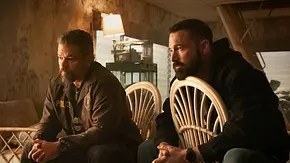 Matt Damon und Ben Affleck sitzen in „The Rip“ auf zwei Plastikstühlen.  - Foto: Claire Folger/Netflix