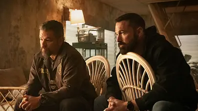 Matt Damon und Ben Affleck sitzen in „The Rip“ auf zwei Plastikstühlen.  - Foto: Claire Folger/Netflix