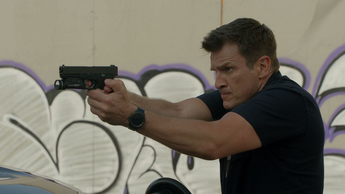 John Nolan zielt in einer Szene aus The Rookie mit seiner Pistole auf etwas außerhalb des Bildes