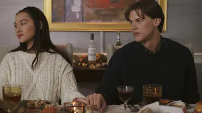 Belly und Conrad sitzen nebeneinander am Tisch und halten Händchen - Foto: Prime Video