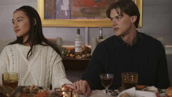Belly und Conrad sitzen nebeneinander am Tisch und halten Händchen - Foto: Prime Video