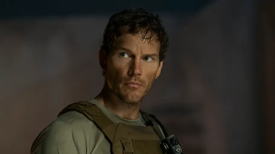 „The Terminal List“ Staffel 2: Reeces Zukunft bleibt offen James Reece trägt ein graugrünes T-Shirt und eine taktische Weste. Er blickt ernst zur Seite vor dunklem Hintergrund.