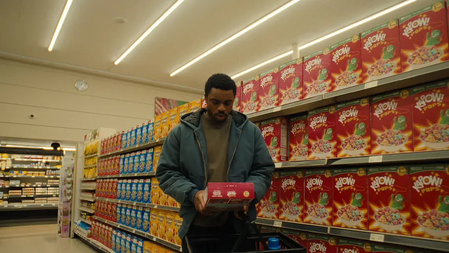 The Vince Staples Show Vince Staples steht in einem ordentlich sortierten Supermarkt und hält eine Packung Cornflakes in der Hand.