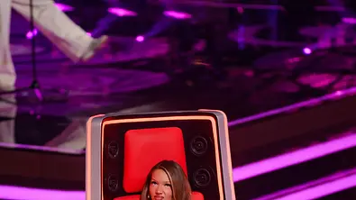 Shirin David sitzt im roten Stuhl von „The Voice“ und hört gespannt zu. - Foto: Joyn Shirin David sitzt im roten Stuhl von „The Voice“ und hört gespannt zu. - Foto: Joyn