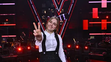 Kandidatin Anne Mosters zeigt Peace in die Kamera. Sie trägt eine weiße Bluse, darüber einen schwarzen Overall. - Foto: Seven.One Entertainment Group GmbH Kandidatin Anne Mosters zeigt Peace in die Kamera. Sie trägt eine weiße Bluse, darüber einen schwarzen Overall. - Foto: Seven.One Entertainment Group GmbH
