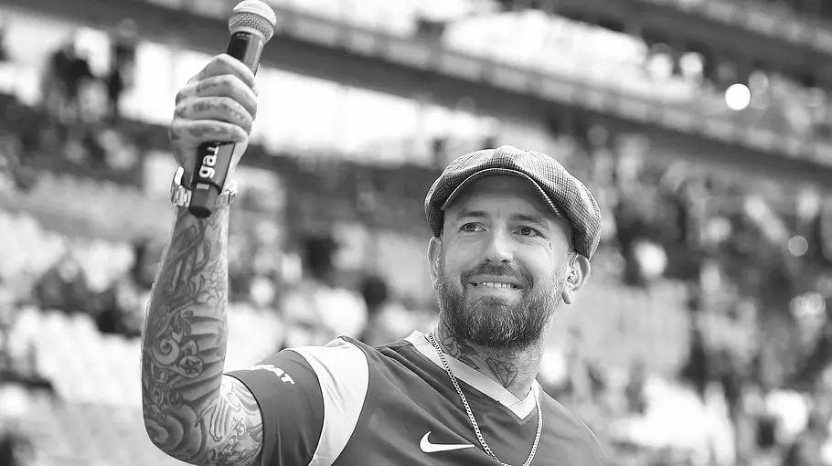 The Voice-Gewinner Ben Saunders ist tot The Voice-Gewinner Ben Saunders, hier in einem Fußballstadion mit erhobenem Mikro, ist tot.