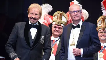 Man sieht Gottschalk und Jauch in zwei Anzügen auf einer Art Karnevalsveranstaltung. Hinter ihnen stehen Personen in entsprechenden Aufzügen. - Foto:  IMAGO / Lindenthaler