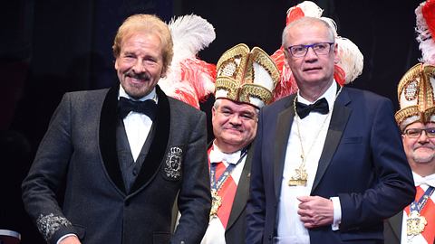 Man sieht Gottschalk und Jauch in zwei Anzügen auf einer Art Karnevalsveranstaltung. Hinter ihnen stehen Personen in entsprechenden Aufzügen. - Foto:  IMAGO / Lindenthaler