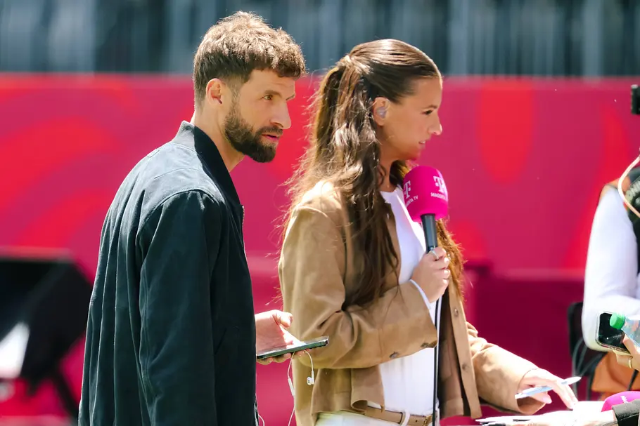 Magenta TV-Experte Thomas Müller und Laura Wontorra mit einem pinken Mikro in der Hand. 