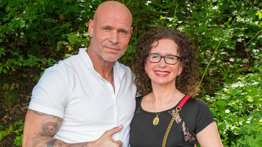 Thorsten und Alexandra Legat Thorsten und Alexandra Legat stehen eng beieinander vor grünen Büschen und halten jeweils einen Daumen nach oben.