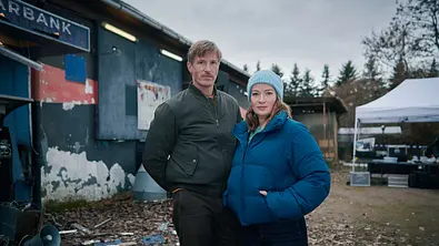 Thüringenkrimi – CASH (AT)“: Moritz Herbst (Golo Euler) und Theresa Wolff (Nina Gummich) stehen mit den Händen in den Taschen vor einer Holzhütte und blicken in die Kamera. - Foto: ZDF / Felix Abraham Thüringenkrimi – CASH (AT)“: Moritz Herbst (Golo Euler) und Theresa Wolff (Nina Gummich) stehen mit den Händen in den Taschen vor einer Holzhütte und blicken in die Kamera. - Foto: ZDF / Felix Abraham