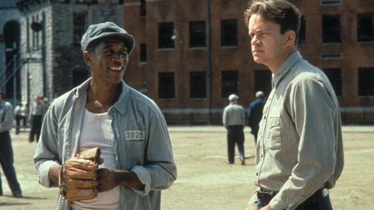 Die Verurteilten Morgan Freeman und Tim Robbins stehen links und rechts im Innenhof eines Gefängnisses.