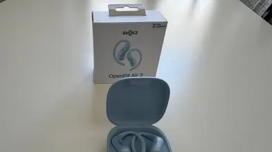 Shokz OpenFit Air 2 im Ladecase vor Produktverpackung auf einem weißen Tisch. - Foto: Privat / Jay Becker