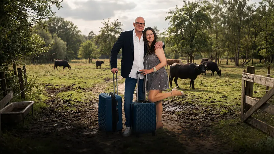 TV-Kommissar Michael Naseband und Shelly Braun mit Koffern vor einer Kuhweide.