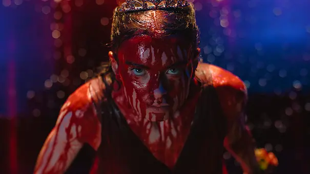 Carrie trägt ein Diadem und ist im Gesicht und am Oberkörper mit Blut bedeckt. Sie blickt vor blau-rotem Hintergrund nach vorn. - Foto: Prime Video Carrie trägt ein Diadem und ist im Gesicht und am Oberkörper mit Blut bedeckt. Sie blickt vor blau-rotem Hintergrund nach vorn. - Foto: Prime Video