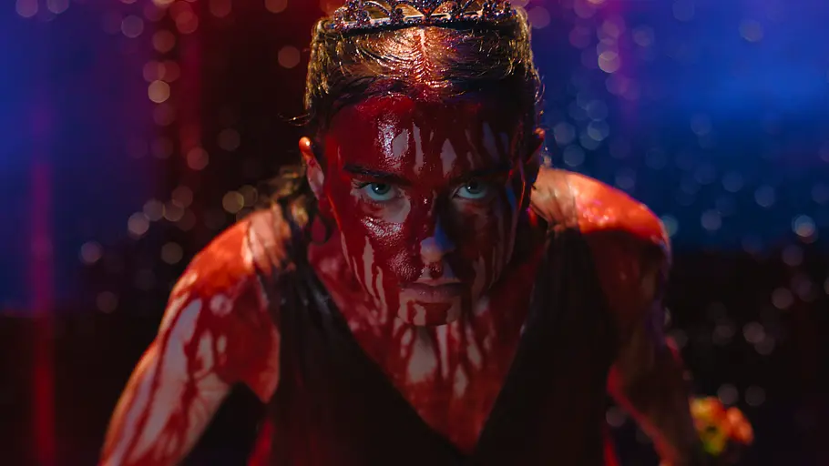 Um das Schweineblut kommt Carrie in keiner Adaption herum. Carrie trägt ein Diadem und ist im Gesicht und am Oberkörper mit Blut bedeckt. Sie blickt vor blau-rotem Hintergrund nach vorn.