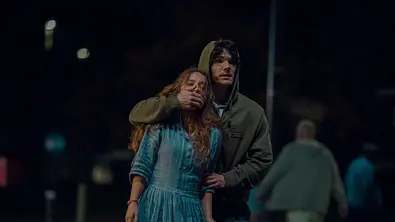 Sam hält seine Hand vor Rosies Mund und packt ihren Arm - Foto: Justin Downing / Netflix