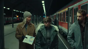 Drei Darsteller der Serie „Unfamiliar“ befinden sich an einem Bahnhof neben einem roten Zug. - Foto: Netflix