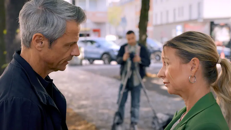 UNTER UNS Vorschau Folge 7989 Stress mit dem Ex Benedikt (Jens Hajek, l.) und Ute (Isabell Hertel) stehen sich ernst gegenüber, während sie von Easy (Lars Steinhöfel, hinten) fotografiert werden.