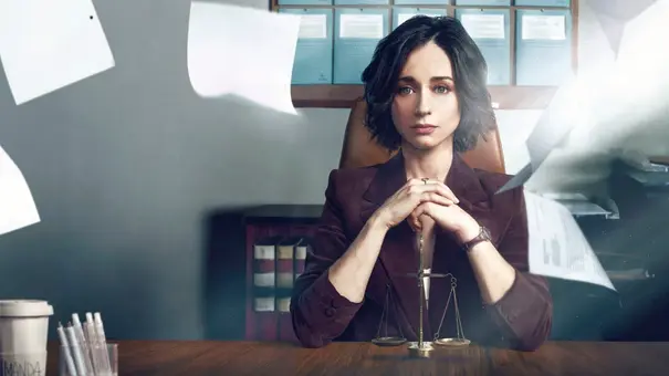 Elena Rivera sitzt an einem Schreibtisch und hat die Hände zusammengefaltet. Um sie herum fliegen Blätter. - Foto: Netflix Elena Rivera sitzt an einem Schreibtisch und hat die Hände zusammengefaltet. Um sie herum fliegen Blätter. - Foto: Netflix