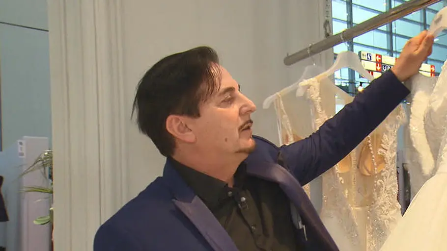 Uwe Hermann arbeitet trotz Krankheit Uwe Hermann in einer Folge von „Zwischen Tüll und Tränen“ mit ausgestrecktem Arm an einer Kleiderstange.