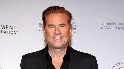 Val Kilmer lächelt vor einer Fotowand. - Foto: IMAGO / APress