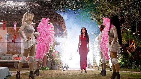 Die neue Princess Vanessa Borck läuft zwischen aufgereihten Tänzer:innen vorbei. Von hinten strahlt ein weißes Licht. Sie trägt ein rotes, enges und langes Kleid. - Foto: RTL