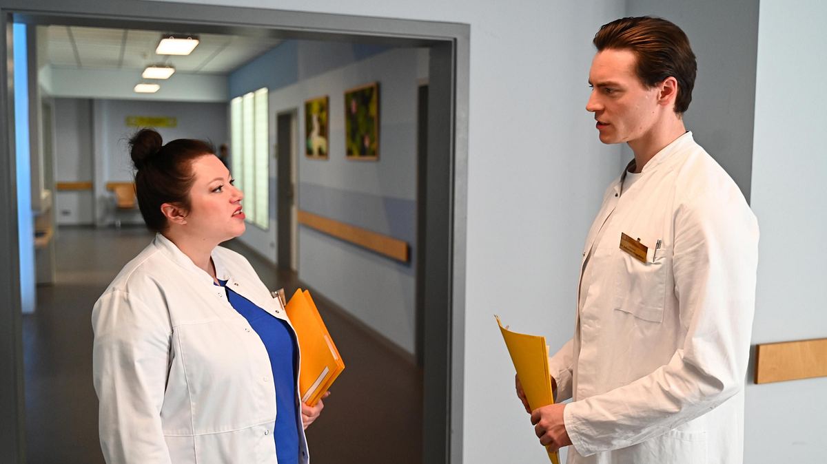 Vanessa und Johannes sind alarmiert. Vanessa und Johannes im Kittel im ernsten Gespräch im Krankenhaus.