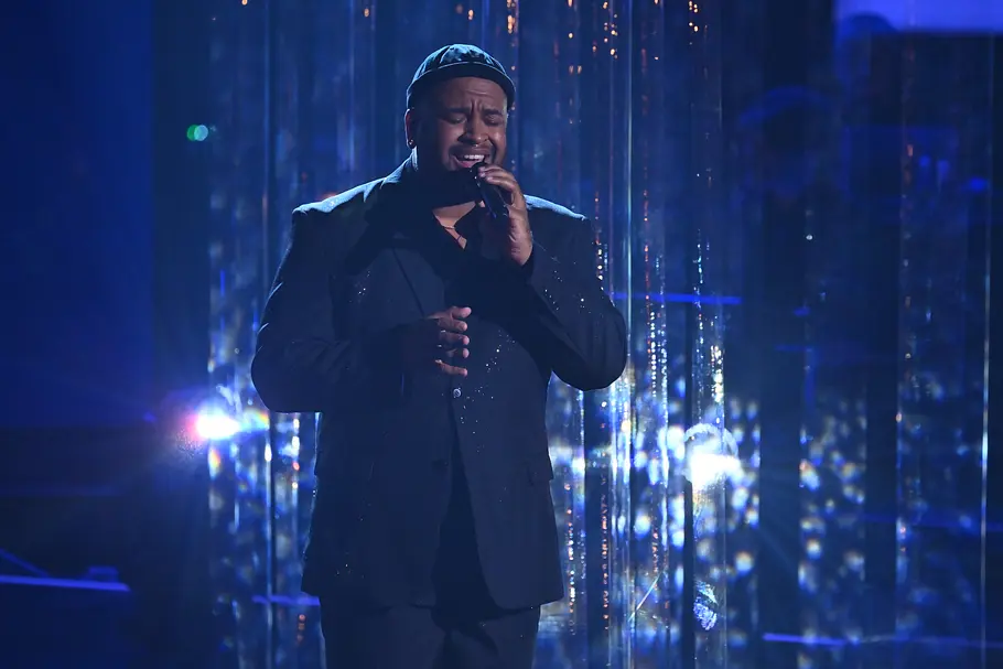Vasco José Mano Halbfinale The Voice 2025 Vasco José Mano singt im Halbfinale. Er trägt einen schwarzen Anzug. Im Hintergrund hängt Dekoration, die spiegelt.