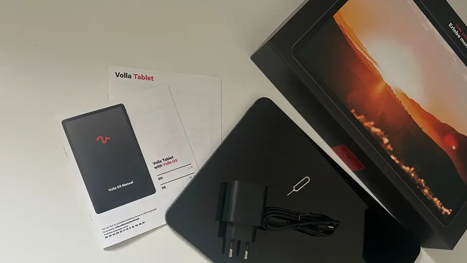 Eine Verpackung des Volla Tablets, zwei Bedienungsanleitungen, das Tablet und Zubehör liegen auf einem weißen Unterrgrund.
