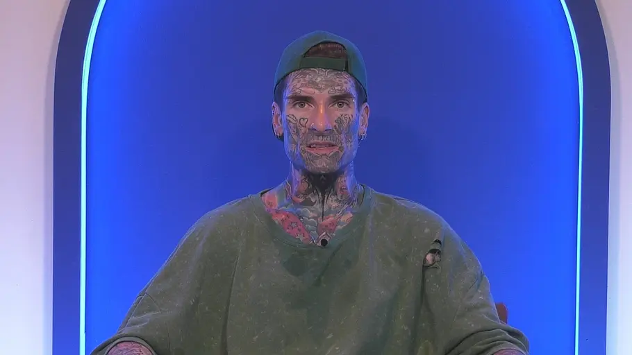 Vielleicht ist es für Nikola besser, dass er nicht noch mehr erzählen konnte. Nikola Grey sitzt mit tätowiertem Gesicht, rückwärts getragener Kappe und löchrigem Shirt vor blau beleuchtetem Hintergrund.