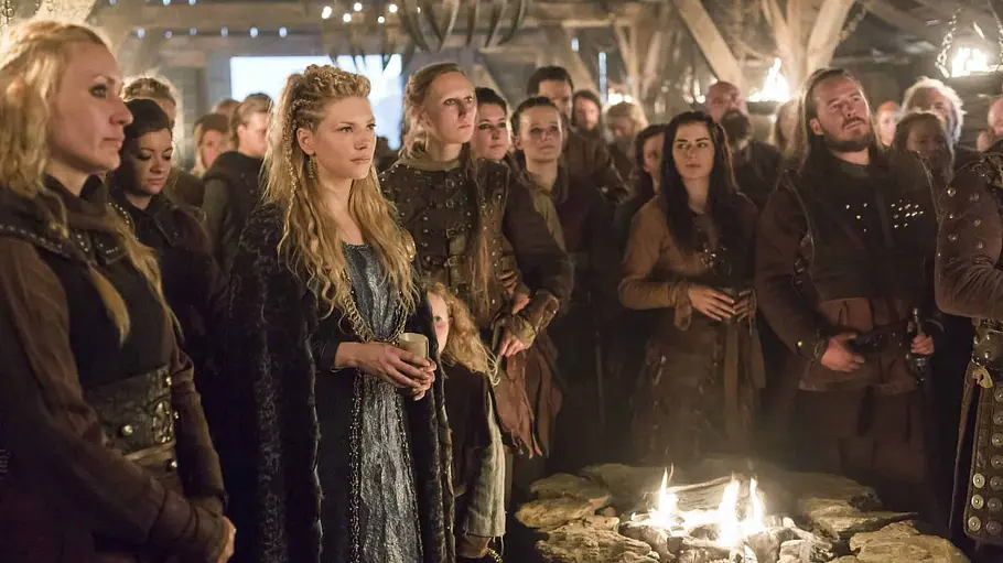 Wikinger stehen versammelt vor einem Feuer in der Serie „Vikings“.